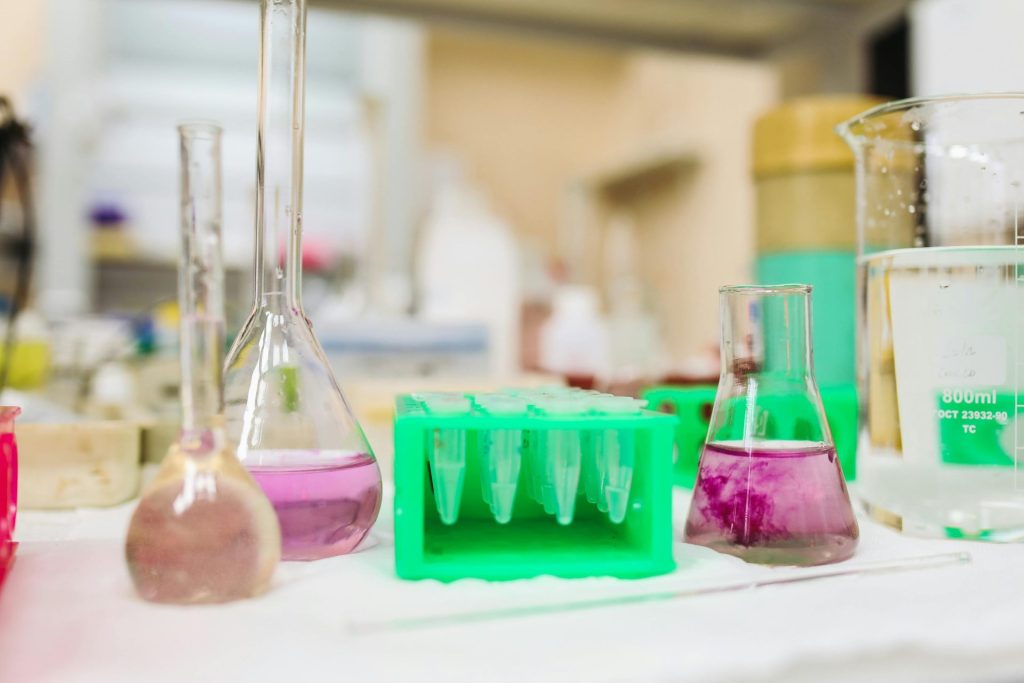Verschiedene Laborglaswaren mit bunten Flüssigkeiten in einem wissenschaftlichen Labor.