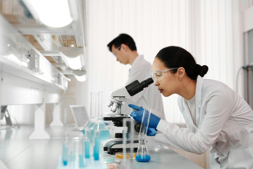 Zwei Wissenschaftler untersuchen Proben unter dem Mikroskop. Fokus auf wissenschaftlicher Forschung und Entdeckung.