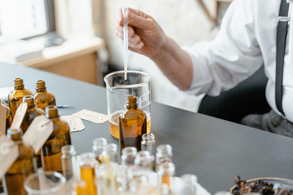 Eine Person mischt ätherische Öle in Glasflaschen für die Aromatherapie im Innenbereich.